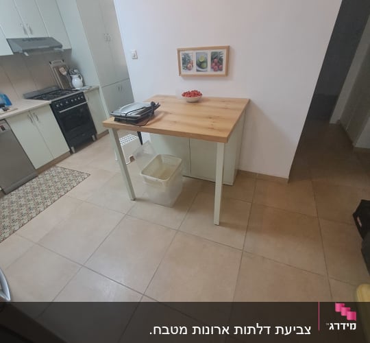 מטבח עם שולחן עץ, גריל חשמלי וקערת עגבניות